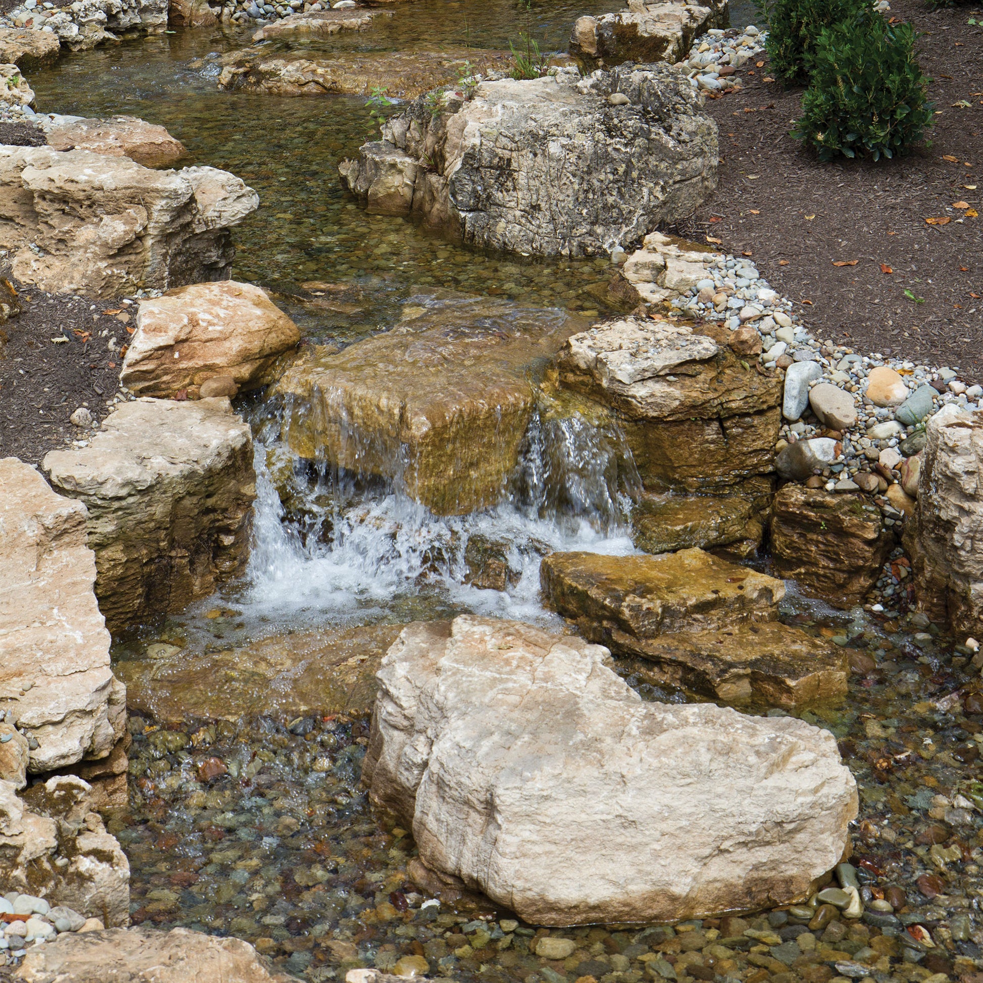 Small waterfall in a natural setting with rocks and water.